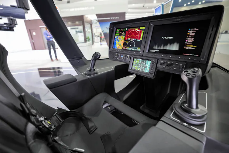 A view inside the cockpit. The controls look like two videogame joysticks with two monitors in between.