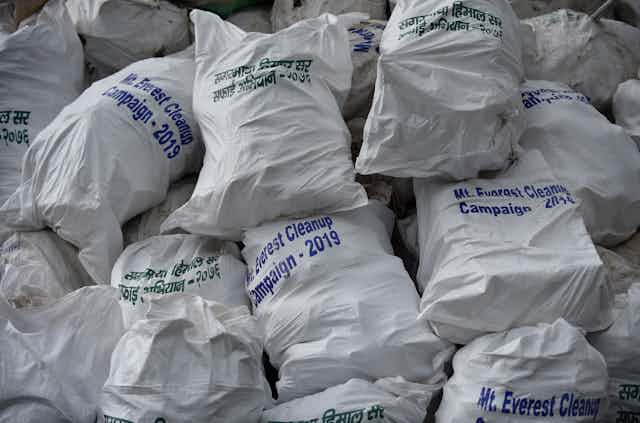 A heap of full sacks labeled 'Mt. Everest Cleanup Campaign – 2019' in English and Nepali