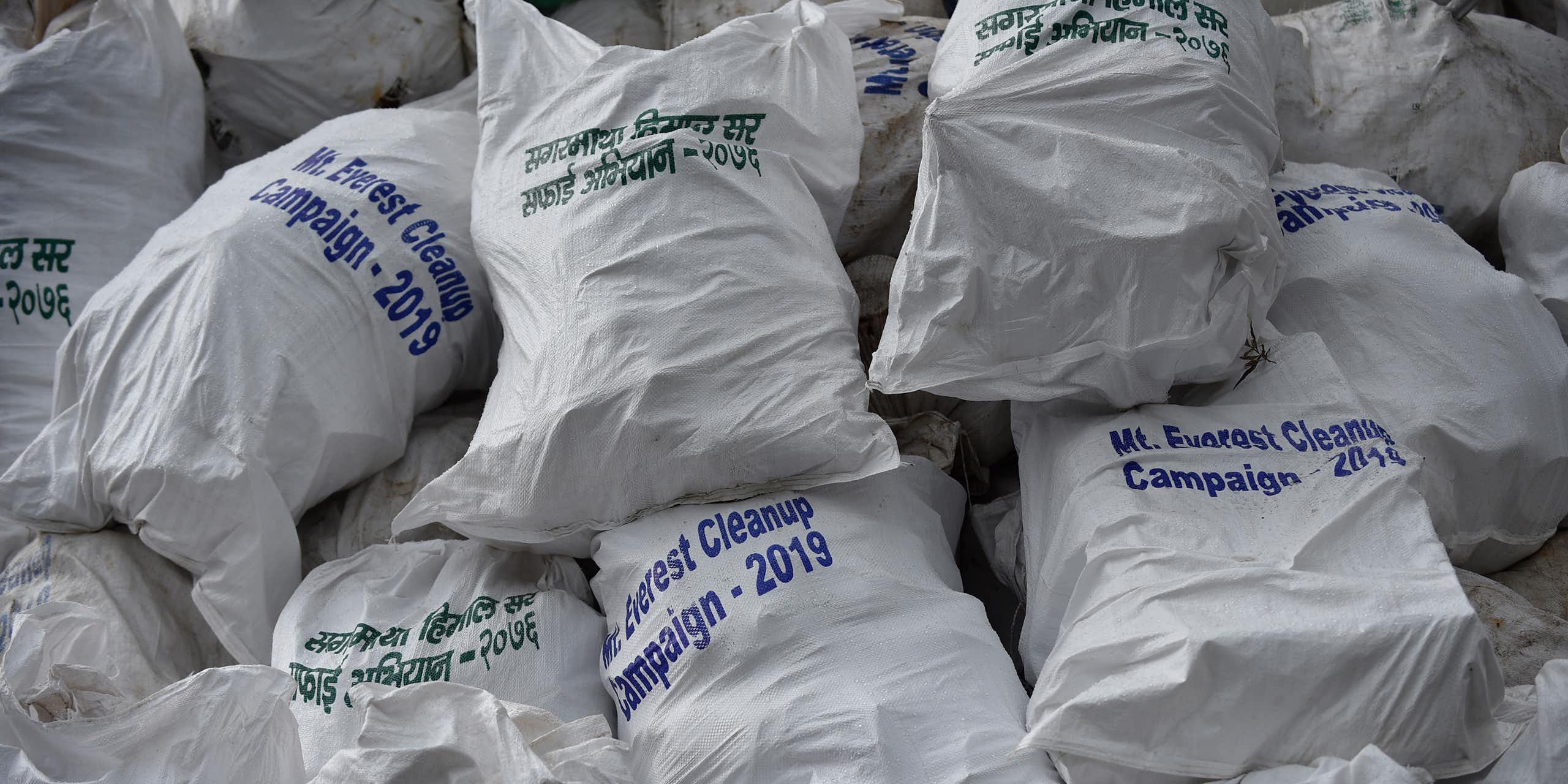 A heap of full sacks labeled 'Mt. Everest Cleanup Campaign – 2019' in English and Nepali