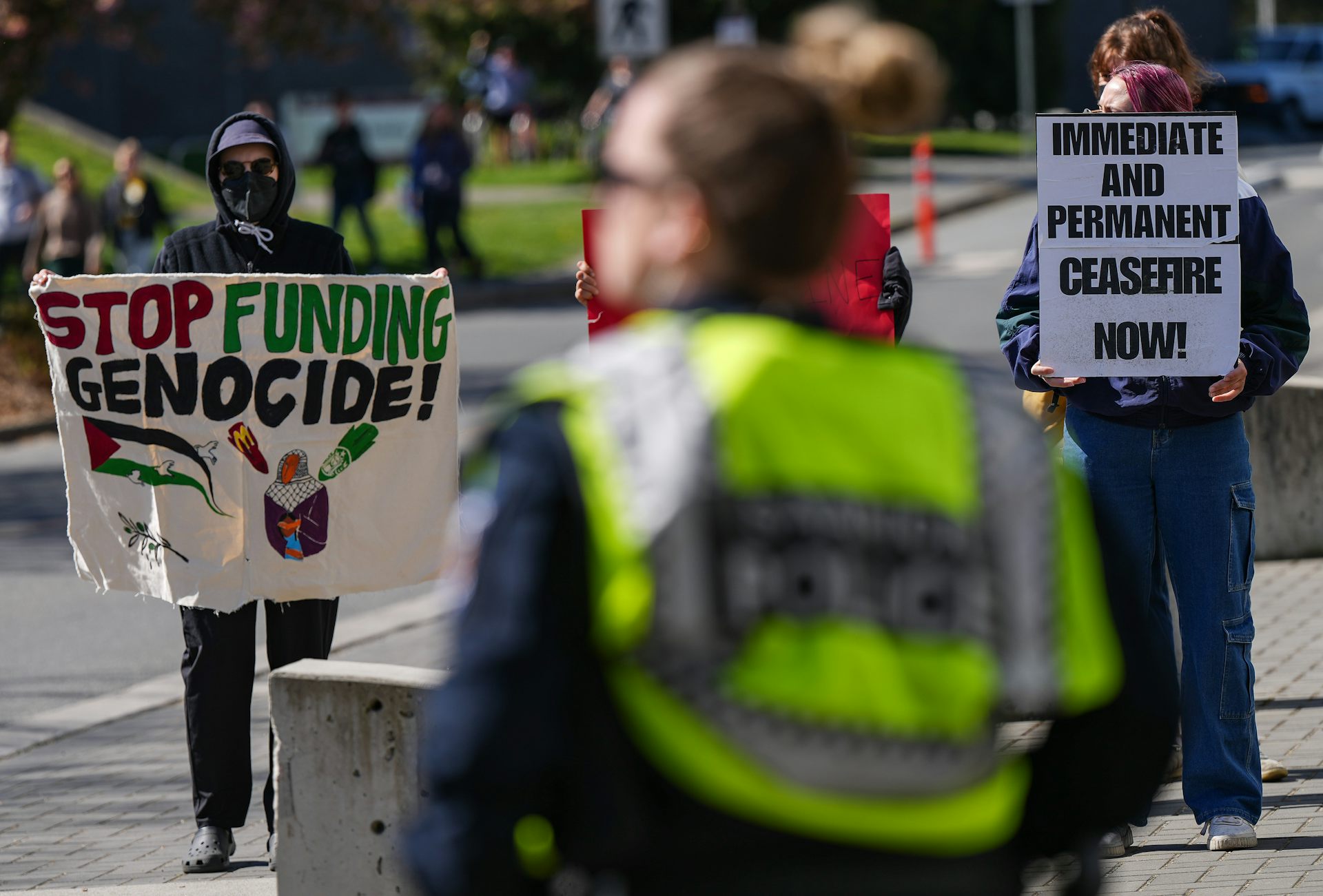 A person seen with banner 'stop funding genocide now.'