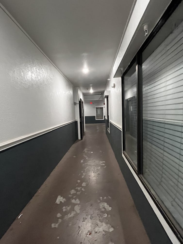 A hallway with paint-scuffed floors illuminated by light bulbs.