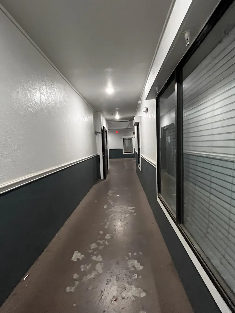 A hallway with paint-scuffed floors illuminated by light bulbs.