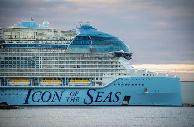 A huge cruise ship docked in the ocean with the words 'Icon of the Seas' written on the side
