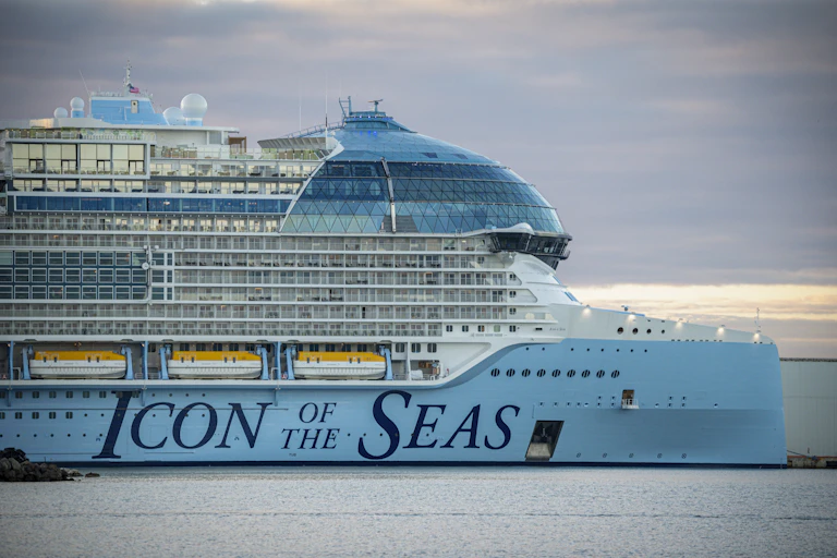 A huge cruise ship docked in the ocean with the words 'Icon of the Seas' written on the side