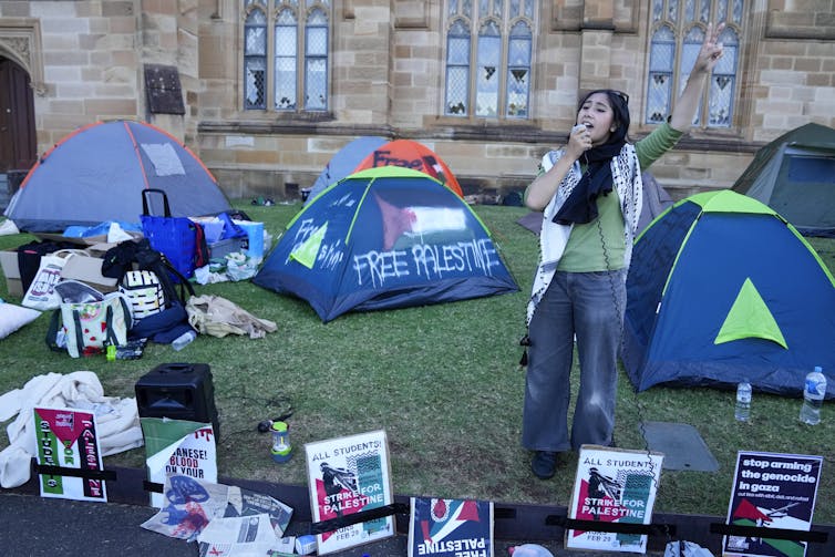 News photograph. Tents, signs and a protester