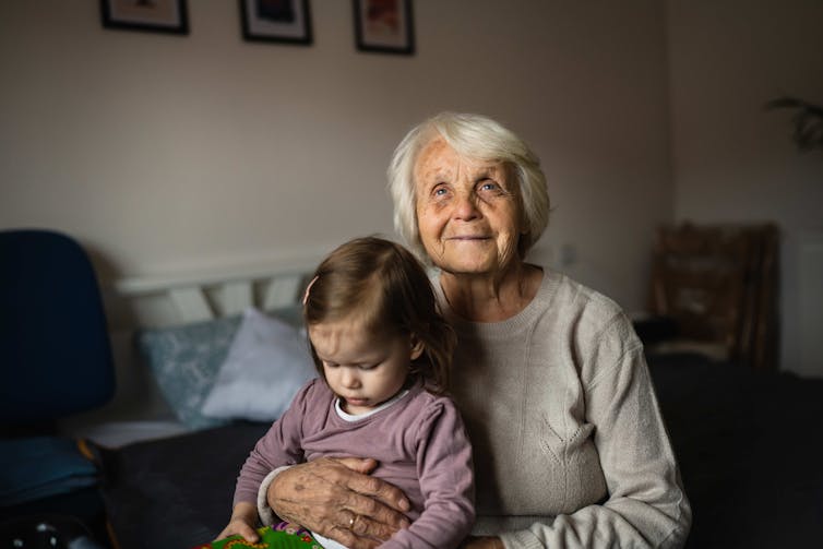 An old woman holds a young girl on her lap.