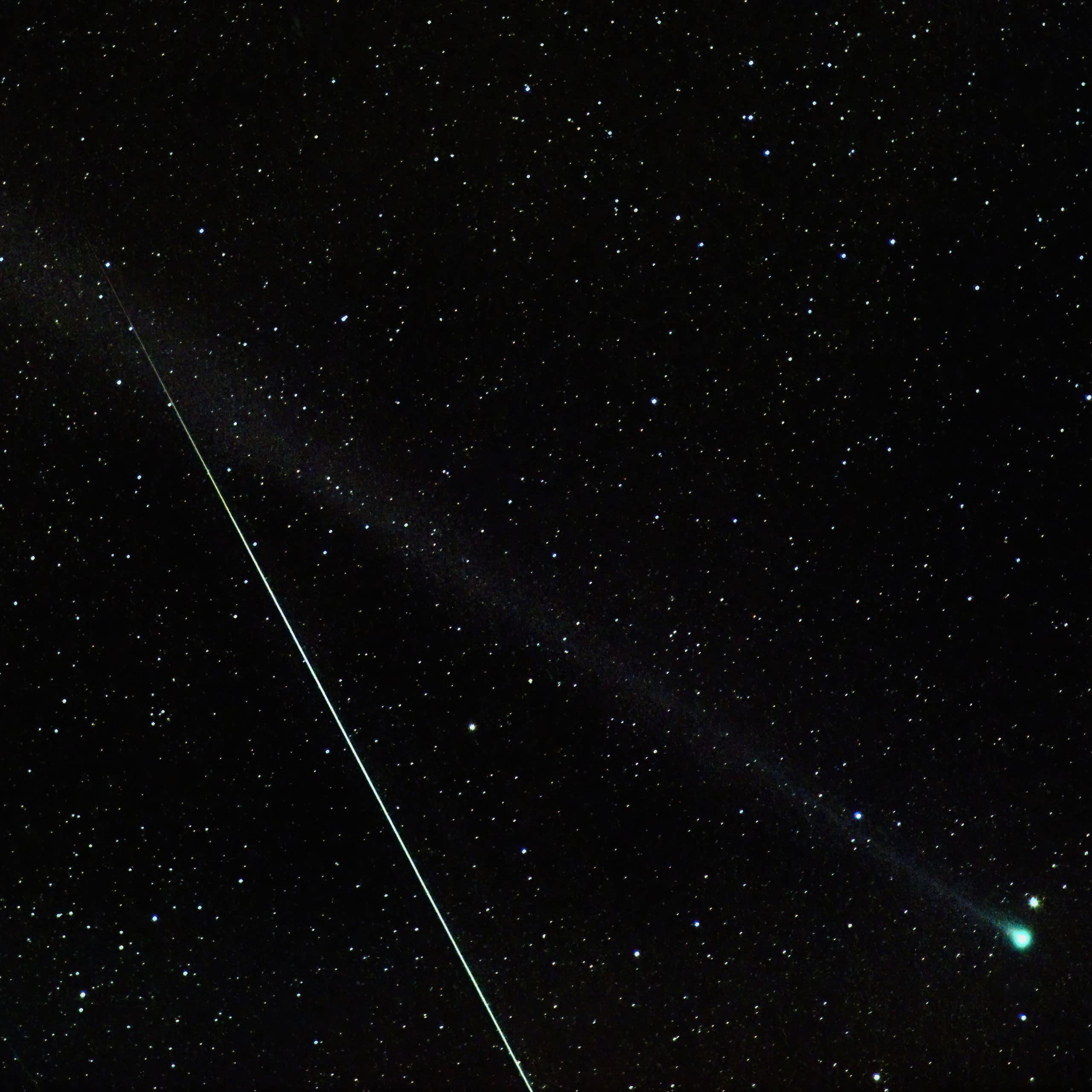 A meteor streaks through a photograph of a green comet.