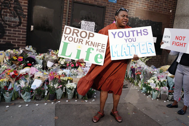 A protestor with placards in front of a memorial.
