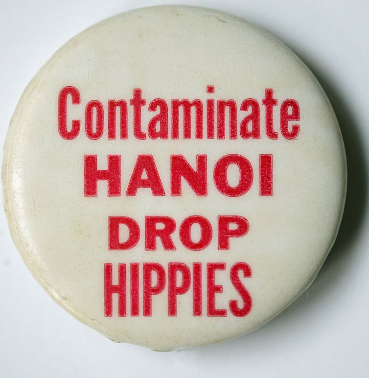 A pin that reads “Contaminate HANOI DROP HIPPIES.”