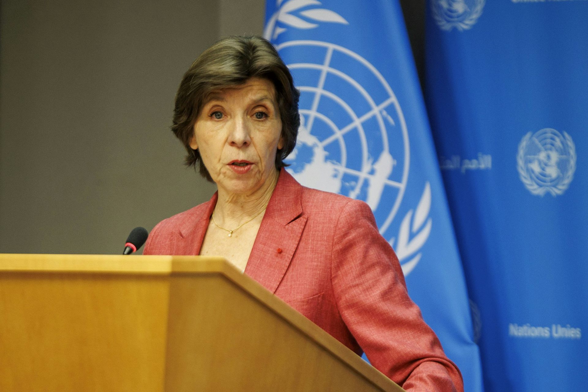Catherine Colonna speaks at a lectern in front of a UN flag