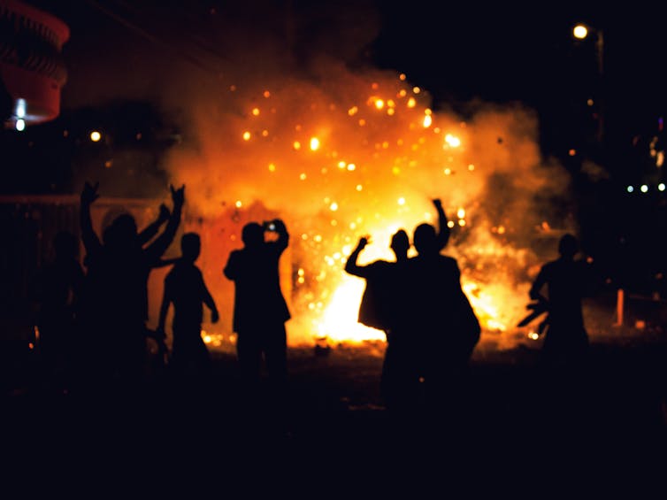 People silhouetted against a fire.