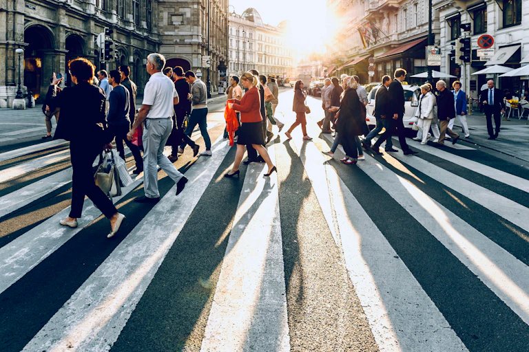People walk across a pedestrian crossing.
