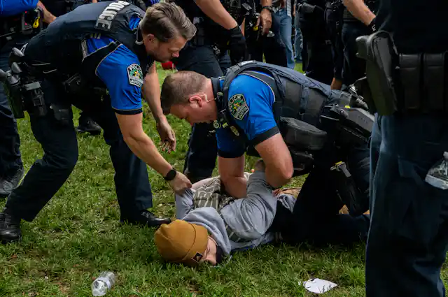 Two police officers arrest a student.