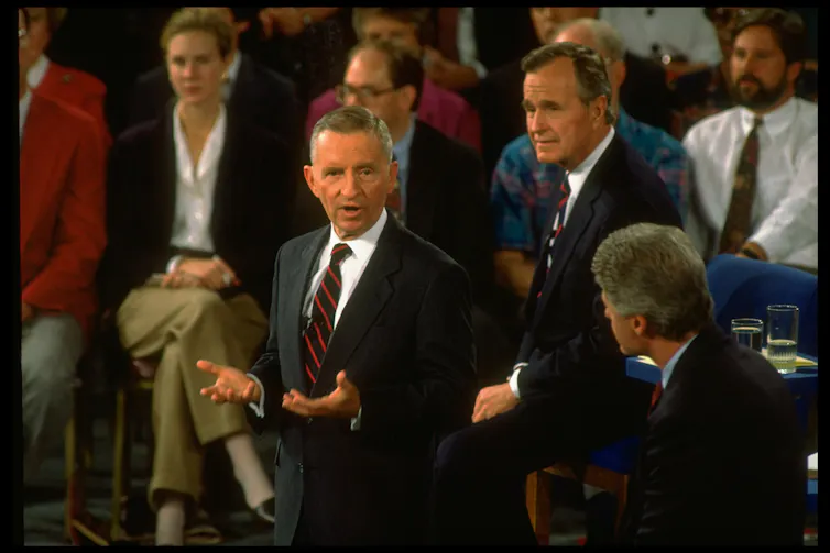 Three men in suits talking with each other while standing.