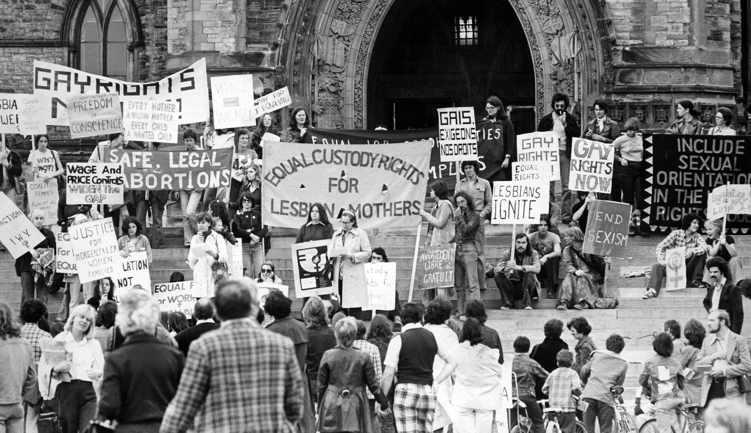 A black and white photo of people at a demonstration with signs calling for equal rights for LGBT people