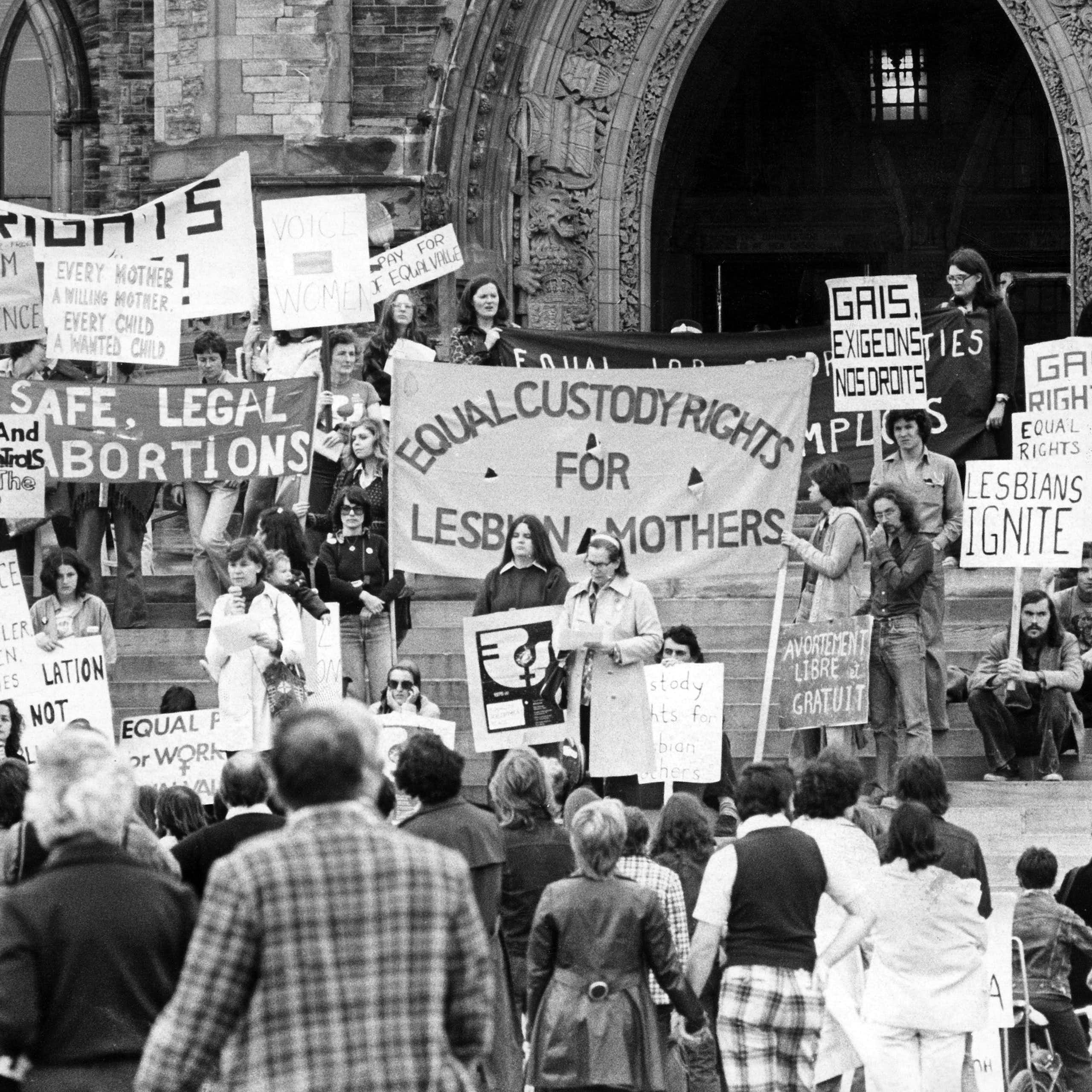 A black and white photo of people at a demonstration with signs calling for equal rights for LGBT people