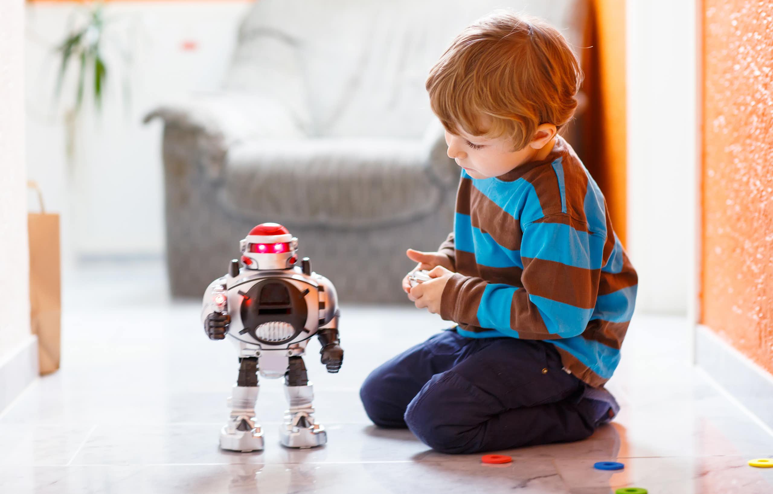 A child sitting on the floor with a robot toy.