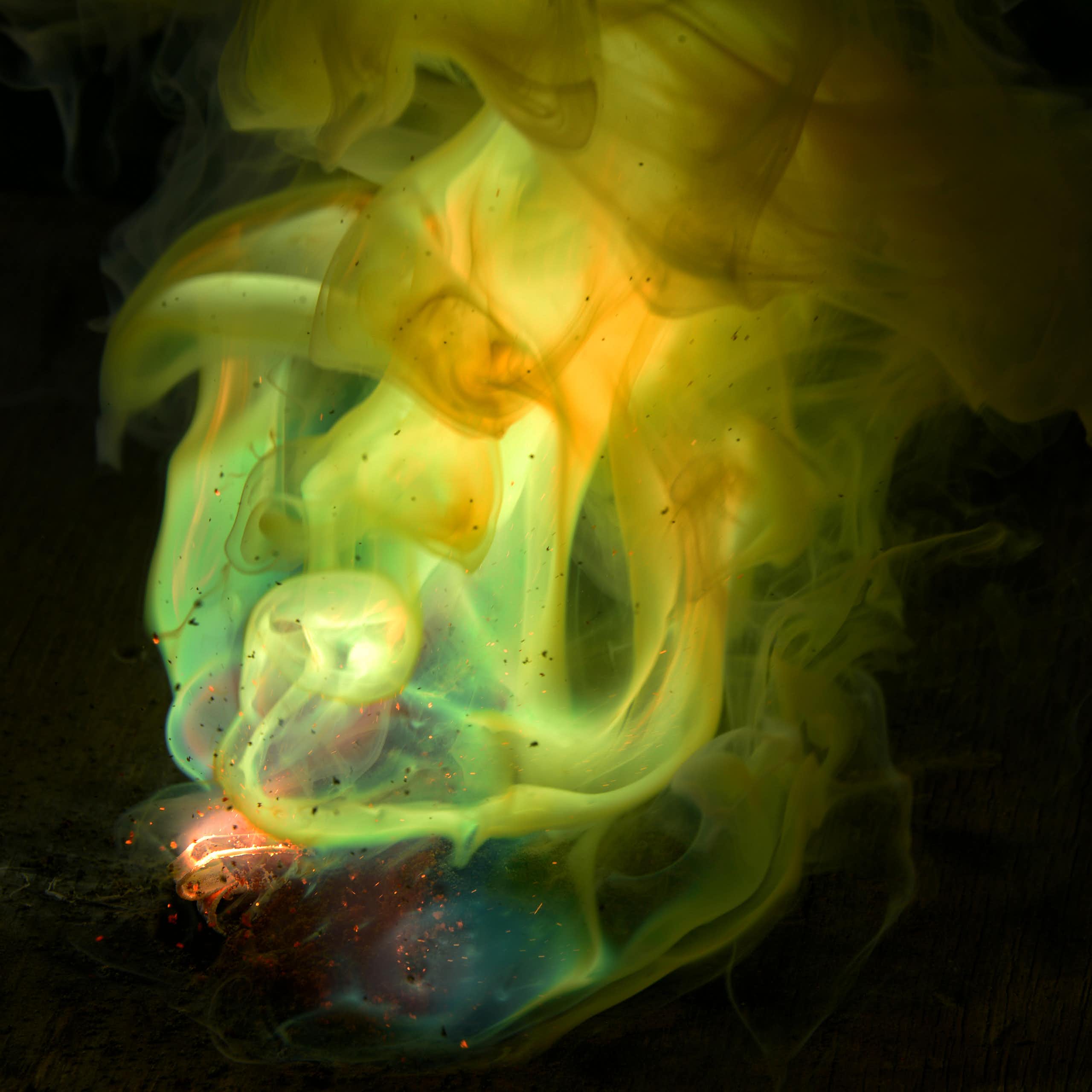 Photo of glowing greenish-yellow chemicals swirling against a dark background.