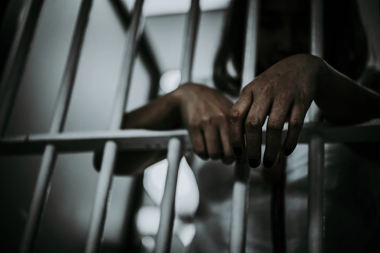 A woman's hands through prison bats