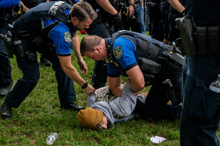 Two police officers arrest a student.
