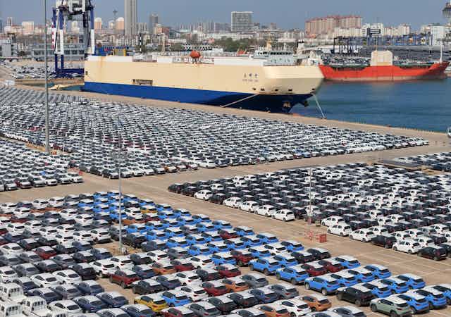 A port car park full of cars waiting to be loaded onto cargo ships.