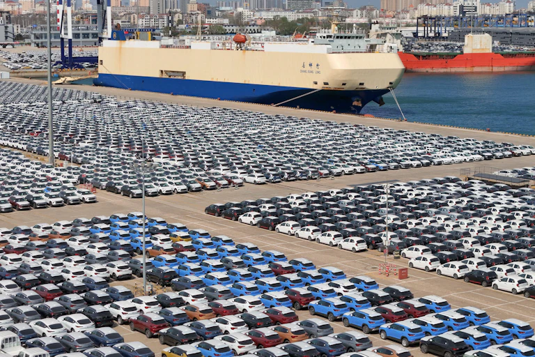 A port car park full of cars waiting to be loaded onto cargo ships.