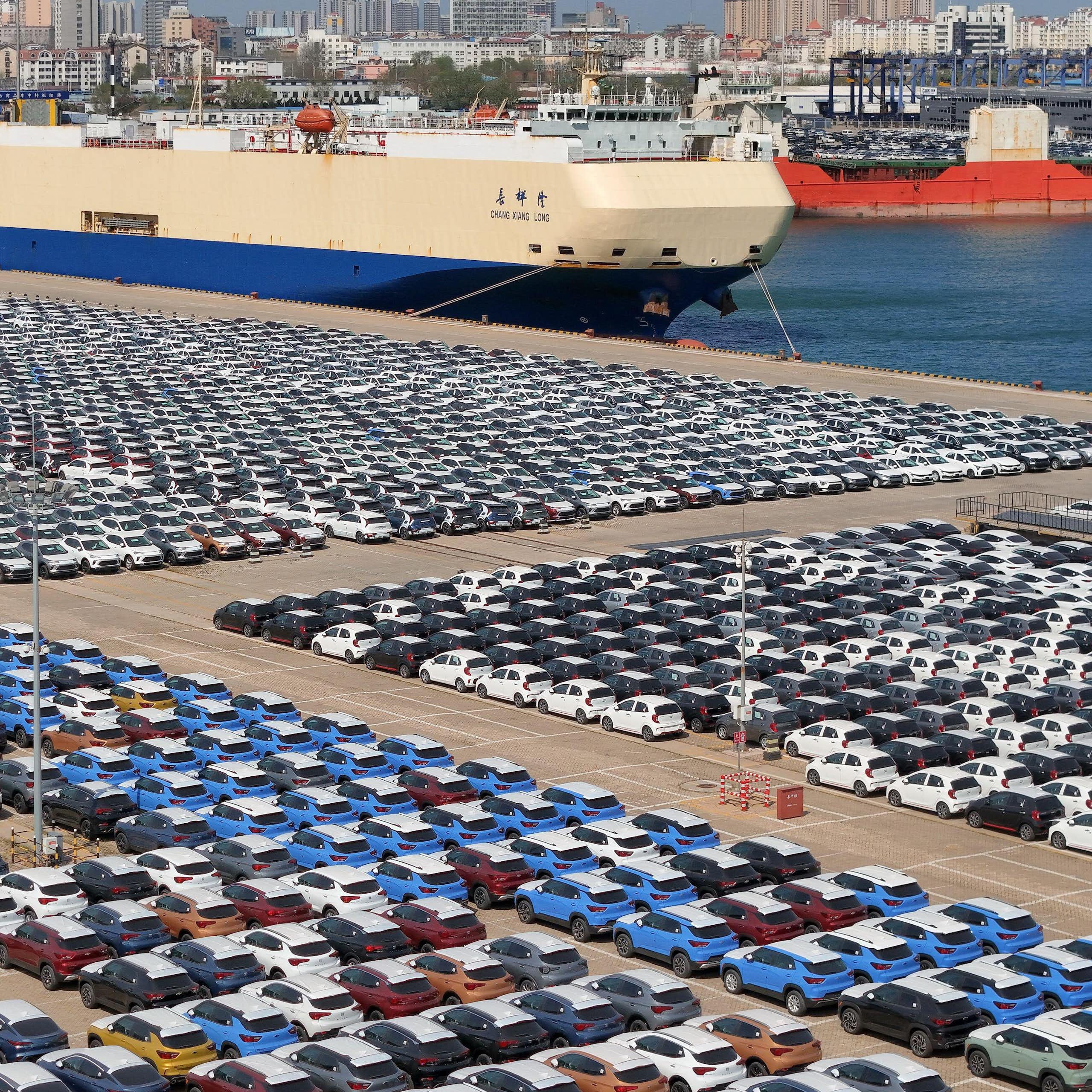 A port car park full of cars waiting to be loaded onto cargo ships.