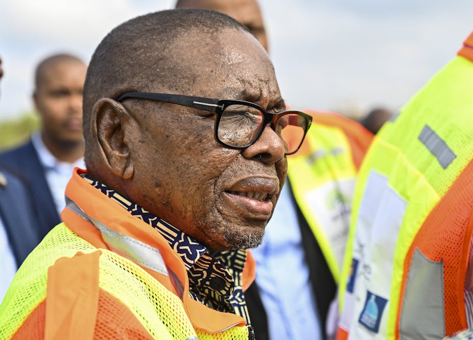 A man wearing a yellow and orange high visibility jacket over a patterned shirt