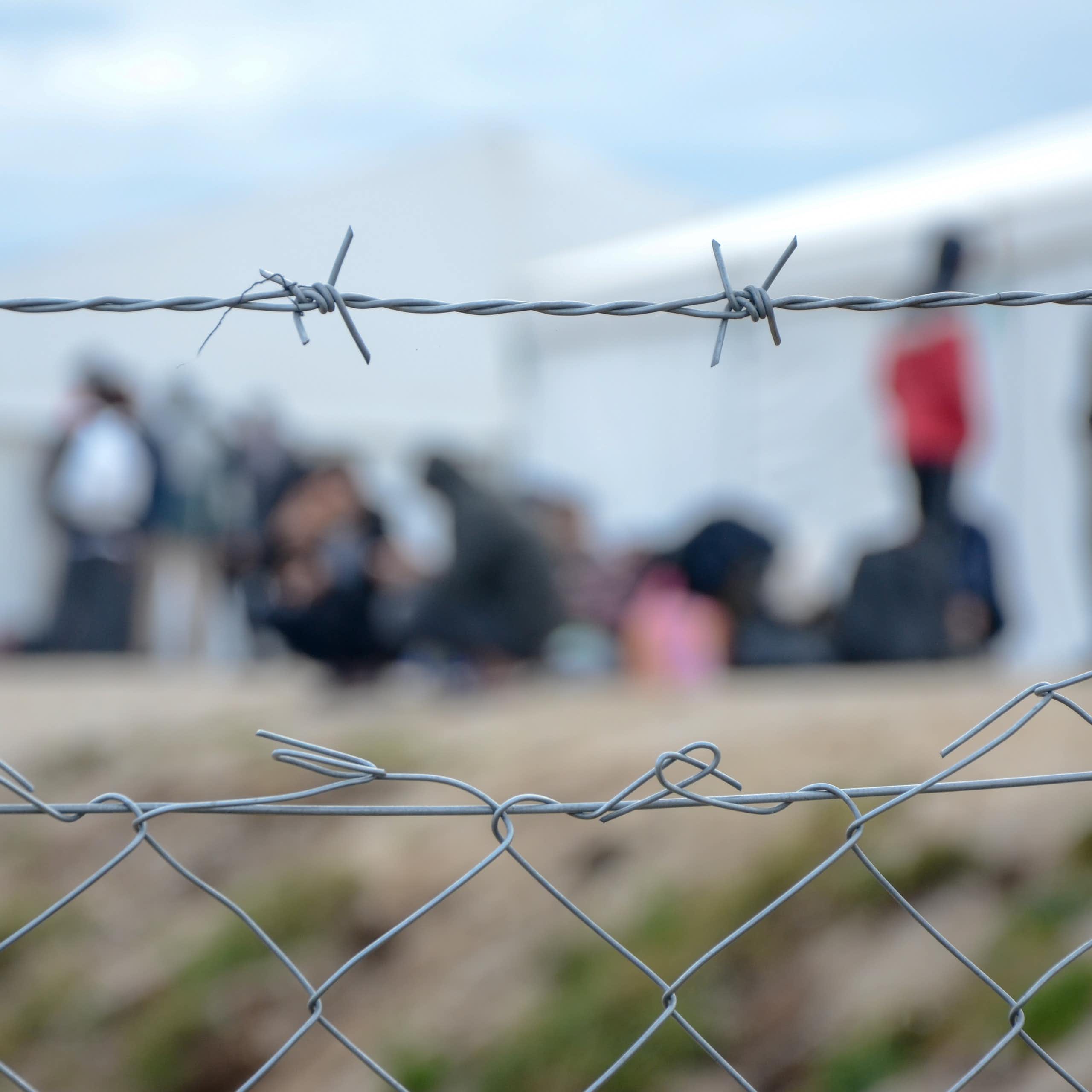 Barbed wire with a group of people in the background, out of focus