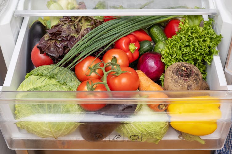 A fridge drawer filled with vegetables.