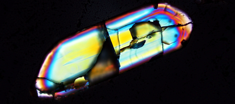 An irregular shape with several colours of blue, yellow, teal, pink and orange on a black background.
