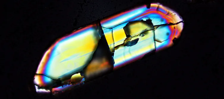 An irregular shape with several colours of blue, yellow, teal, pink and orange on a black background.