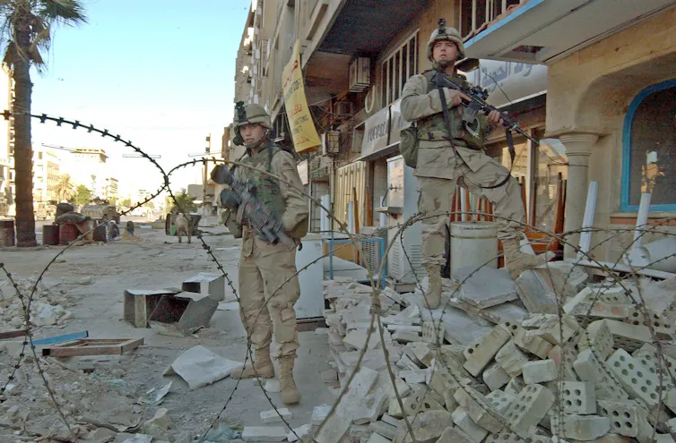 US servicemen stand in rubble in front of a Bghdad hotel that was hit by US fire in April 2003.