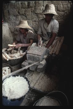 two women in hats peeling and shredding tubers