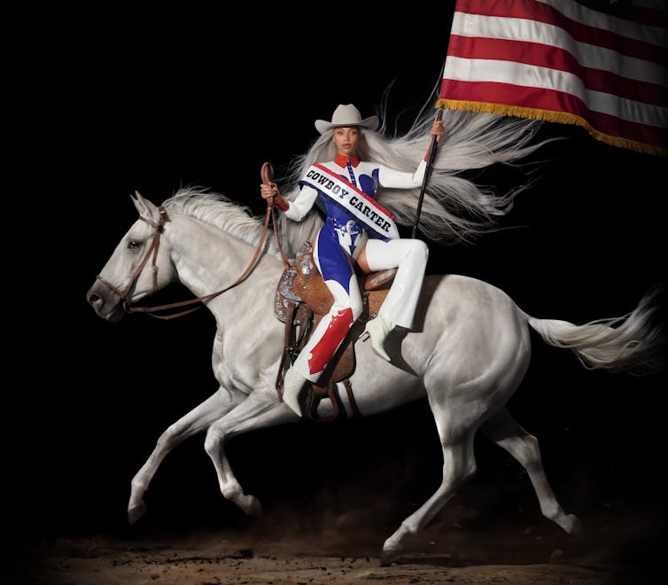 Beyonce riding a white horse side saddle and waving the American flag.