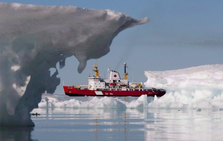 A red-and-white icebreaker boat amid ice bergs.