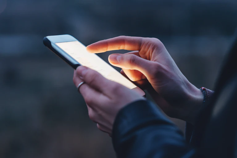 Closeup image of female hands using modern smartphone at night