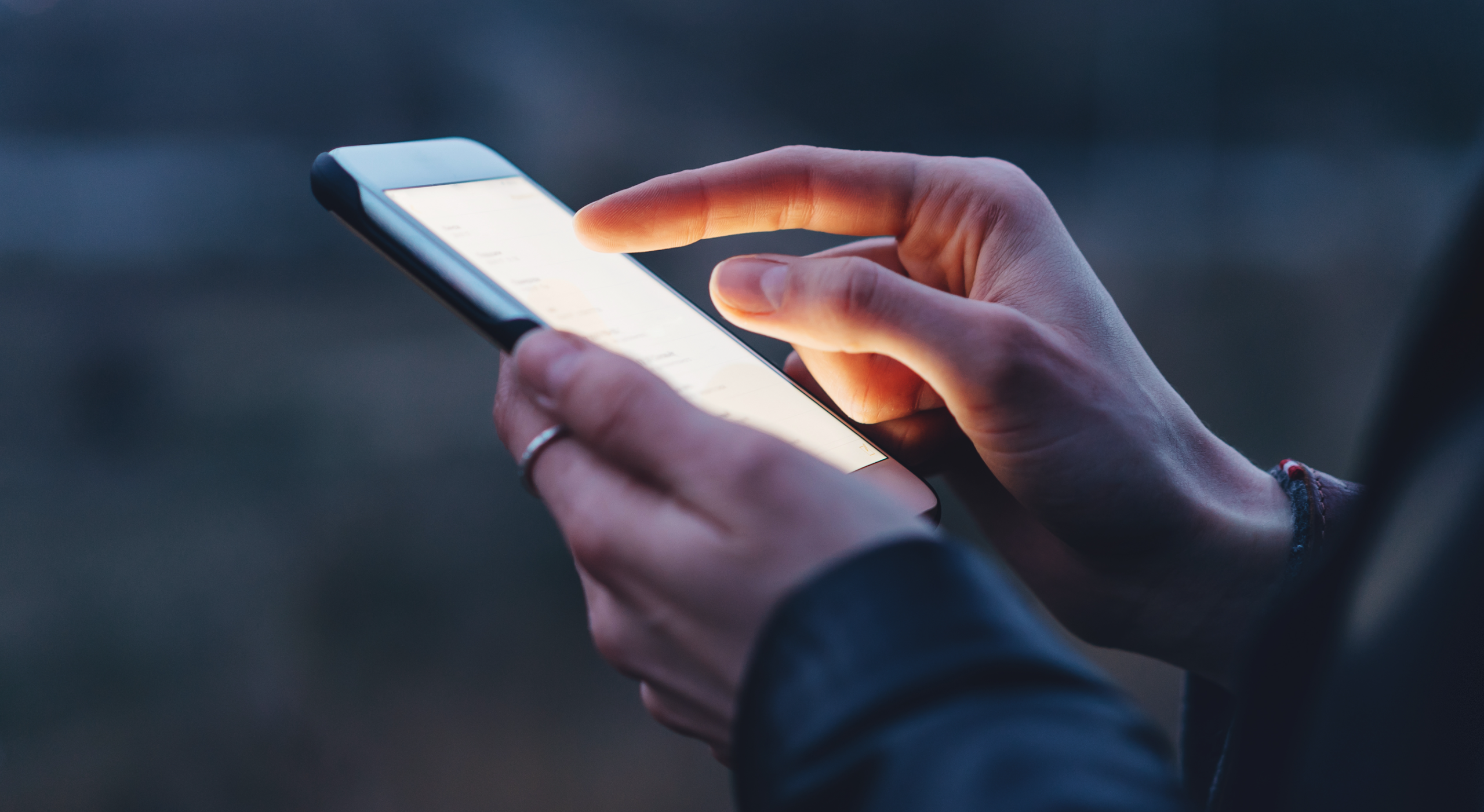 Closeup image of female hands using modern smartphone at night