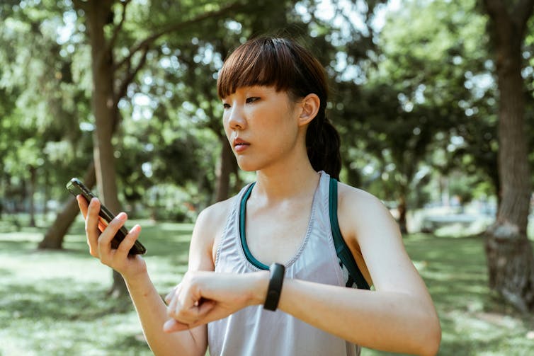 A woman with an activity tracker on her wrist looking at a smartphone.