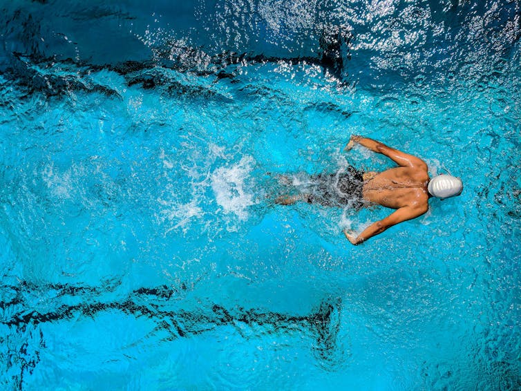 Bird's eye view of a man swimming in a pond.