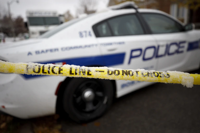 A police care with yellow police tape line in the foreground