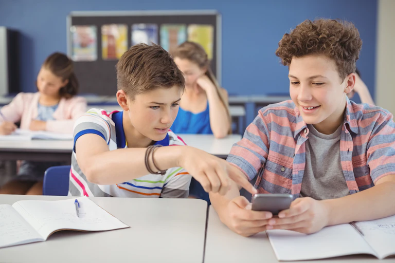 School pupils in class looking at mobile phone