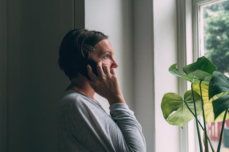 A woman on the phone looks out of a window.
