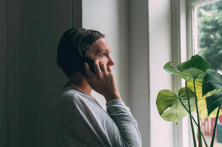 A woman on the phone looks out of a window.