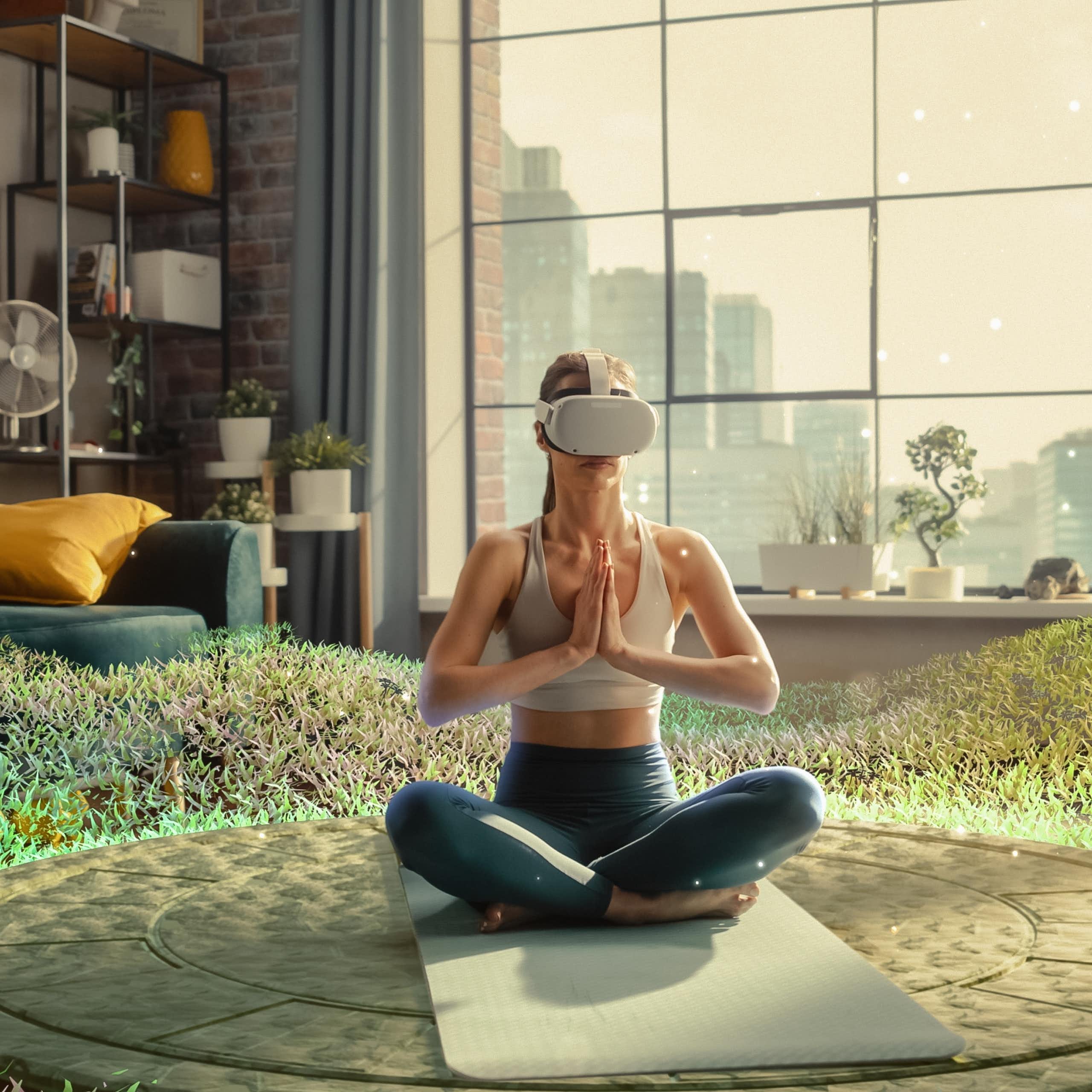 A woman wearing VR goggles places her hands together while sitting on the ground. Virtual greenery surrounds her. 