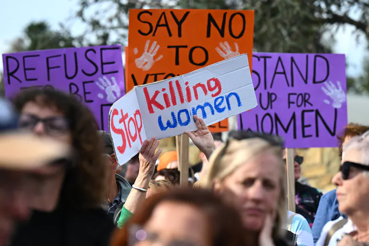 People hold up signs as they attend a rally to a call for action to end violence against women, in Canberra, Sunday, April 28, 2024.
