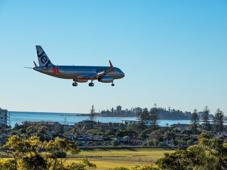 Jetstar plane lands at Gold Coast airport, city seen in background