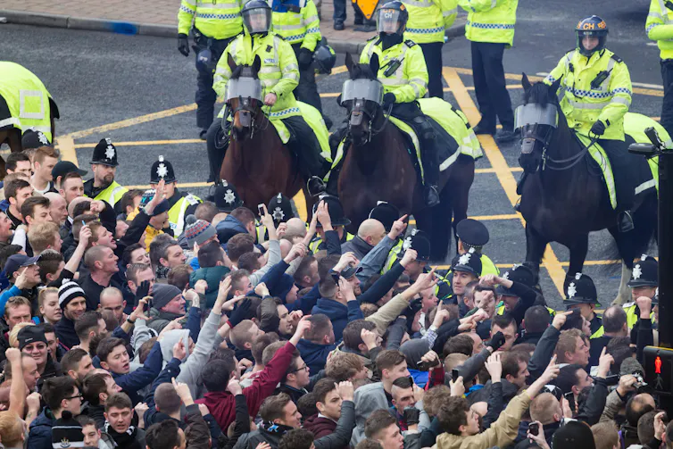 Mounted police watch crowd of football fans.