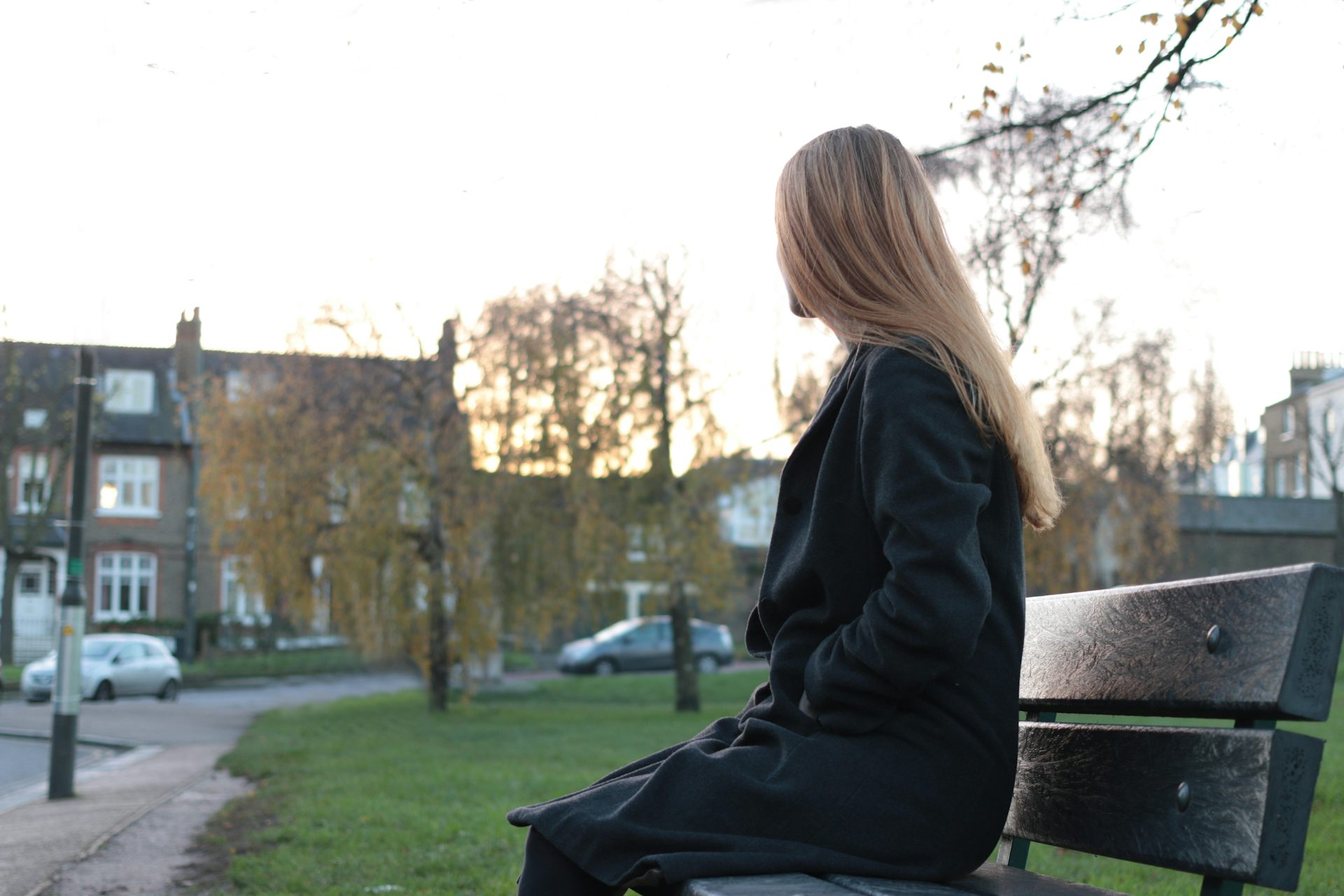 Woman sitting on a park bench, staring into the distance.