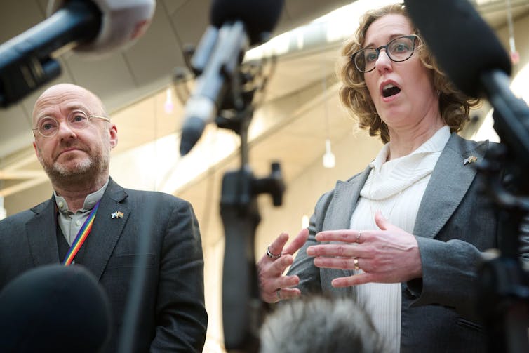 Two politicians speaking into microphones.